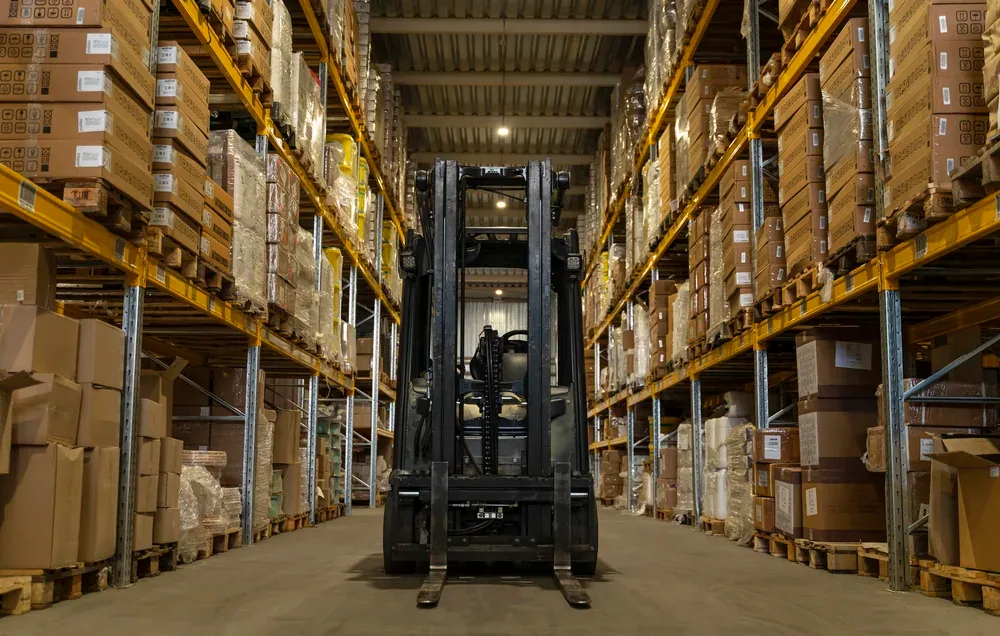 Forklift operating between warehouse storage racks